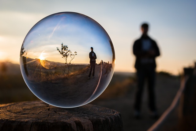 Plaatje van een man die reflecteert in een luchtbel terwijl hij buiten staat voor op de pagina Die With Zero