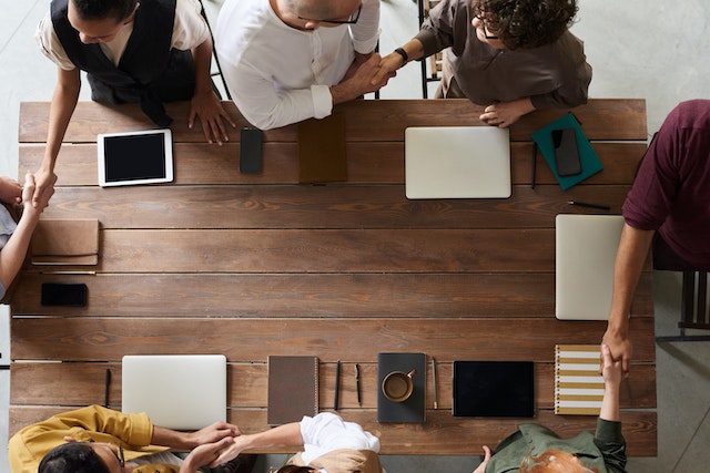 Foto van mensen om een tafel met laptops voor de blog bedrijfsovername